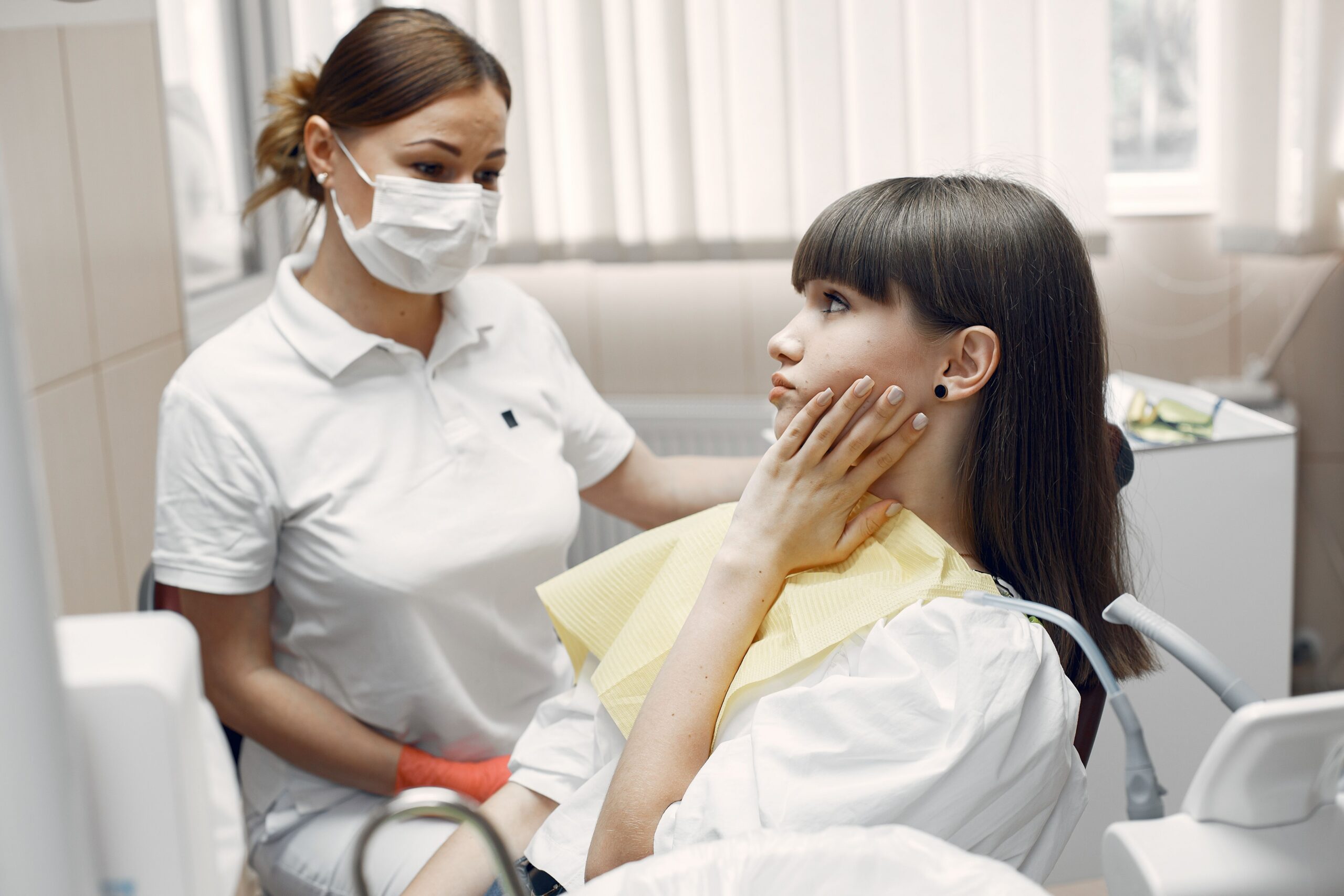 Dentist examining a patient experiencing tooth pain during a dental appointment.