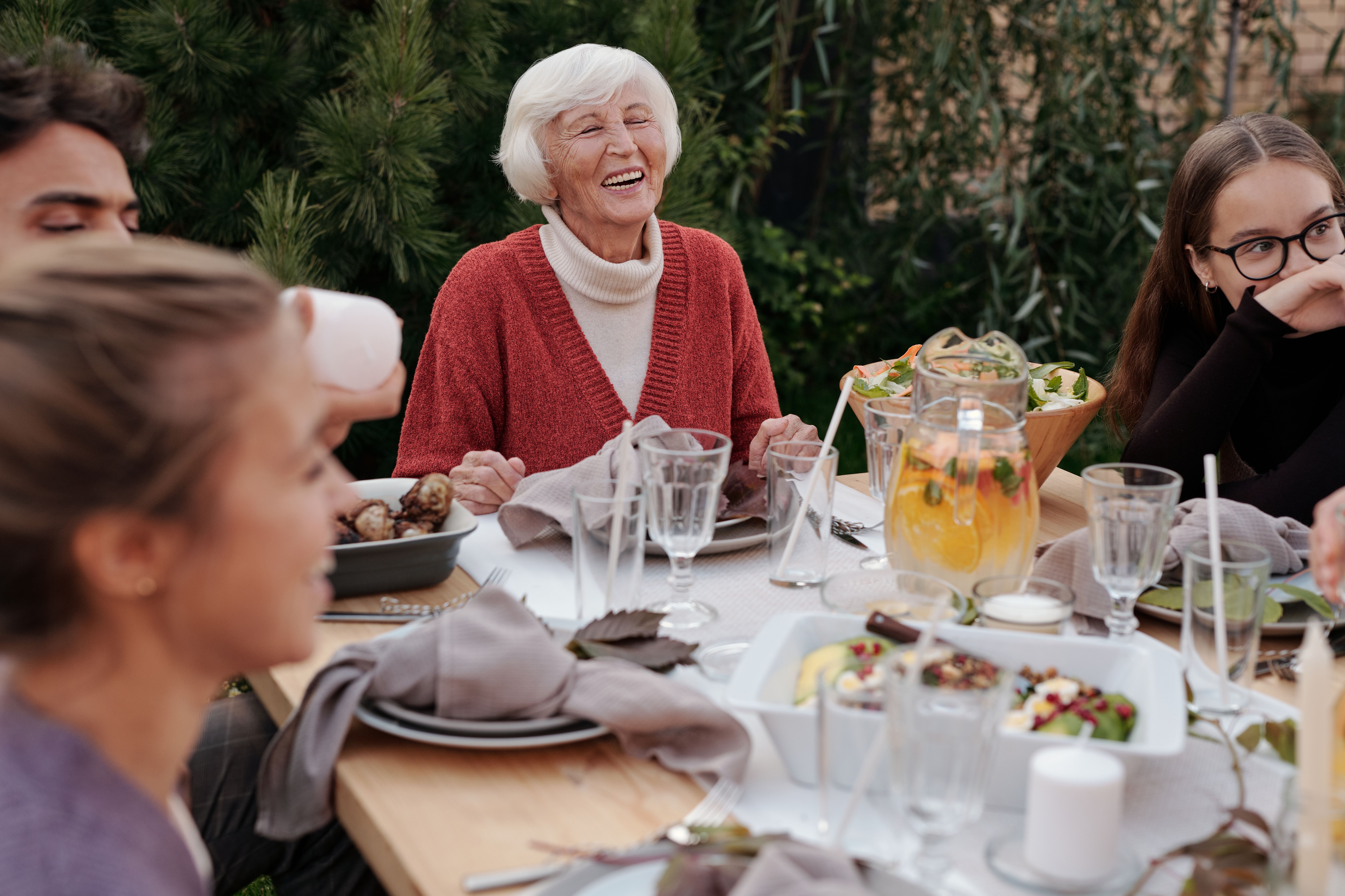 Older adult enjoying a meal with family after adjusting to dentures.