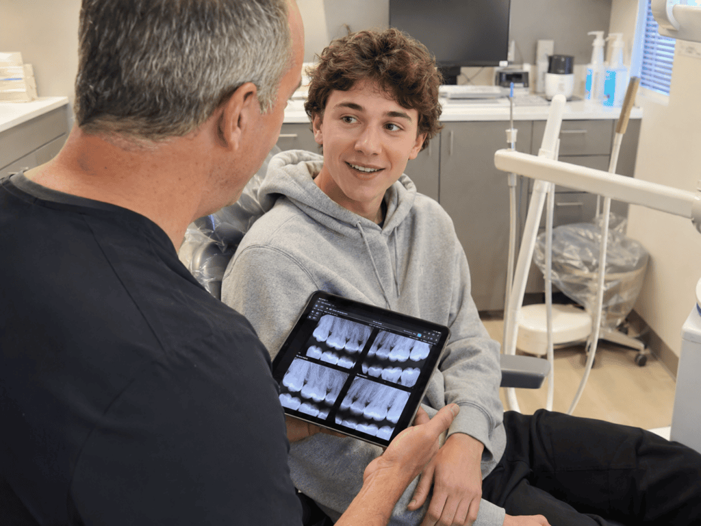 Teenager discussing oral health with a family dentist during a routine dental visit.